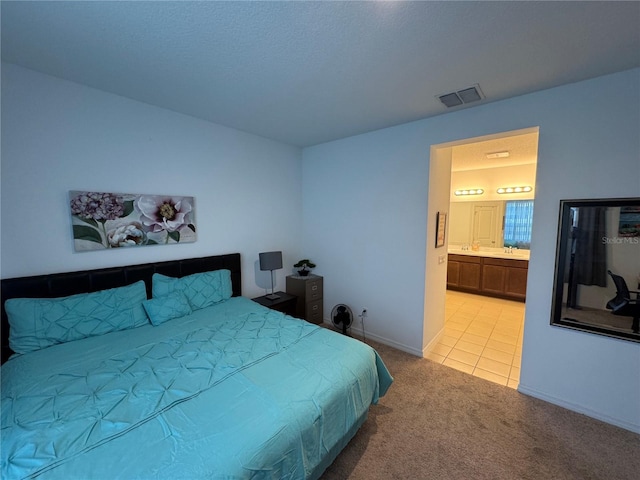 bedroom featuring ensuite bathroom and light carpet