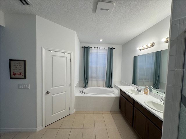 bathroom with vanity, tile patterned floors, tiled bath, and a textured ceiling