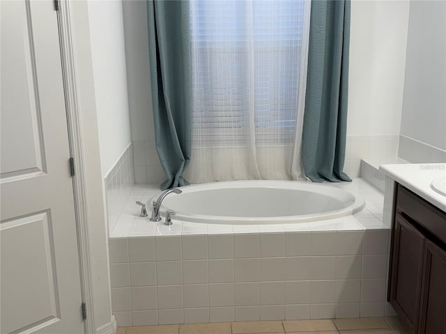 bathroom featuring a relaxing tiled tub, tile patterned floors, and vanity