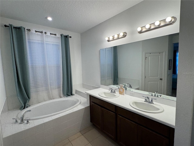 bathroom with vanity, a relaxing tiled tub, tile patterned floors, and a textured ceiling