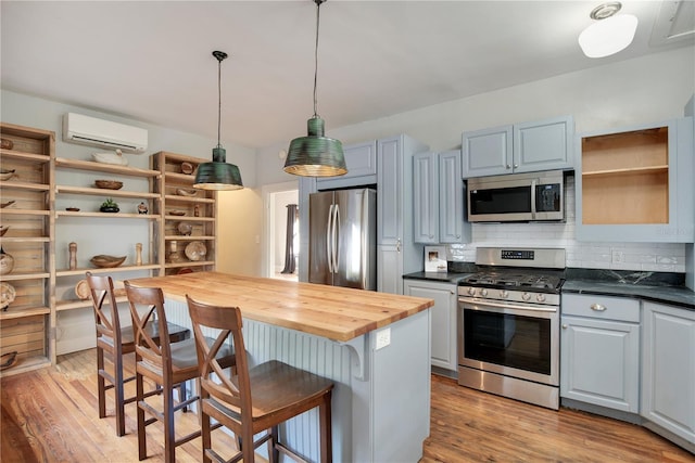 kitchen featuring light hardwood / wood-style flooring, stainless steel appliances, a wall mounted AC, tasteful backsplash, and wood counters