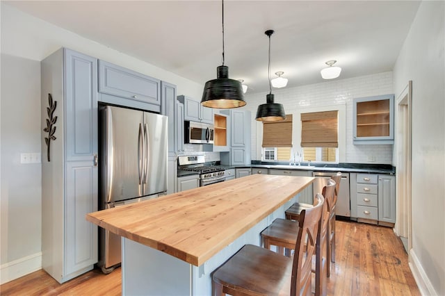 kitchen with decorative light fixtures, a kitchen bar, decorative backsplash, a center island, and stainless steel appliances