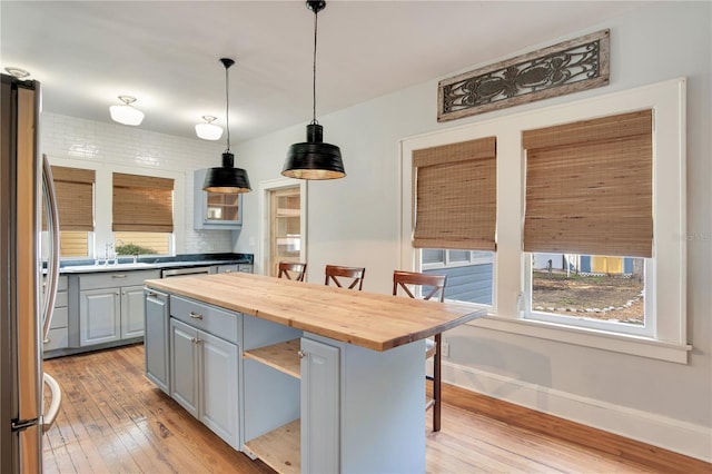 kitchen featuring wooden counters, stainless steel fridge, gray cabinets, a kitchen breakfast bar, and a kitchen island