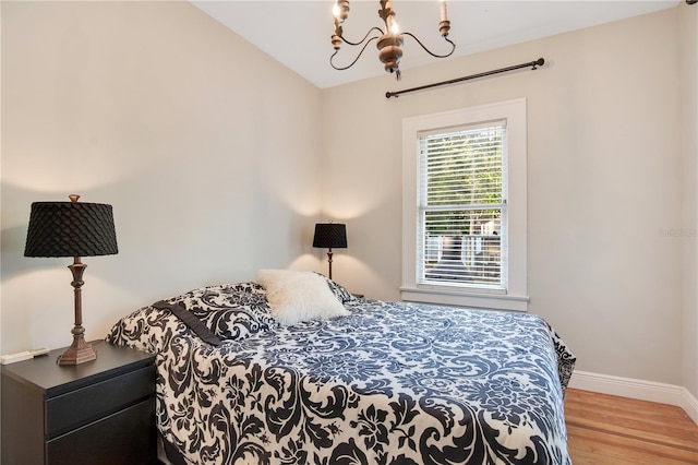 bedroom featuring an inviting chandelier and light hardwood / wood-style floors