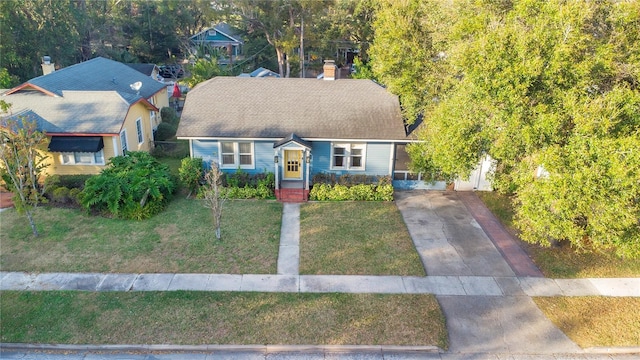 view of front of house with a shingled roof, a chimney, a front lawn, and concrete driveway