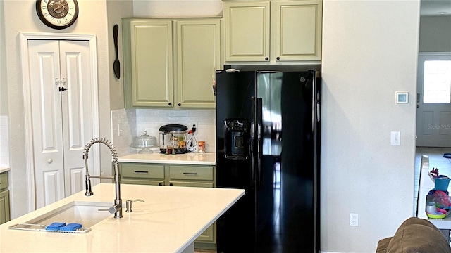 kitchen with sink, backsplash, and black refrigerator with ice dispenser