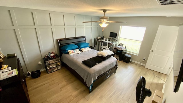 bedroom with ceiling fan, light hardwood / wood-style flooring, and a textured ceiling