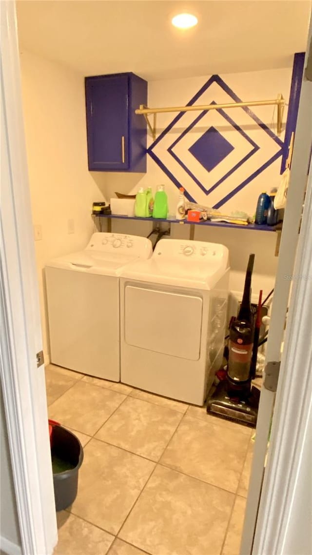 laundry area featuring separate washer and dryer, light tile patterned floors, and cabinets