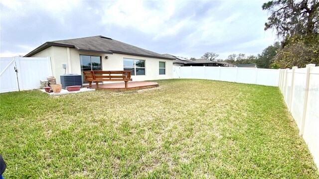 back of house featuring a wooden deck, central AC unit, and a lawn