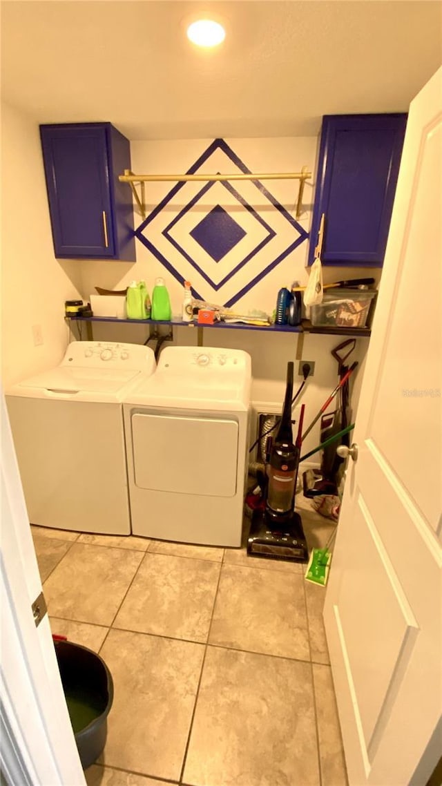 laundry area with light tile patterned floors, electric panel, cabinets, and washing machine and clothes dryer