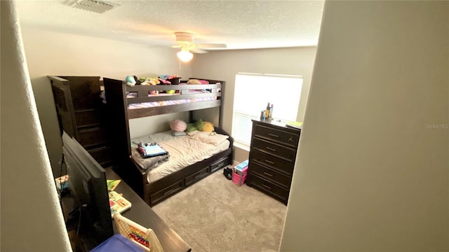 carpeted bedroom featuring ceiling fan and a textured ceiling