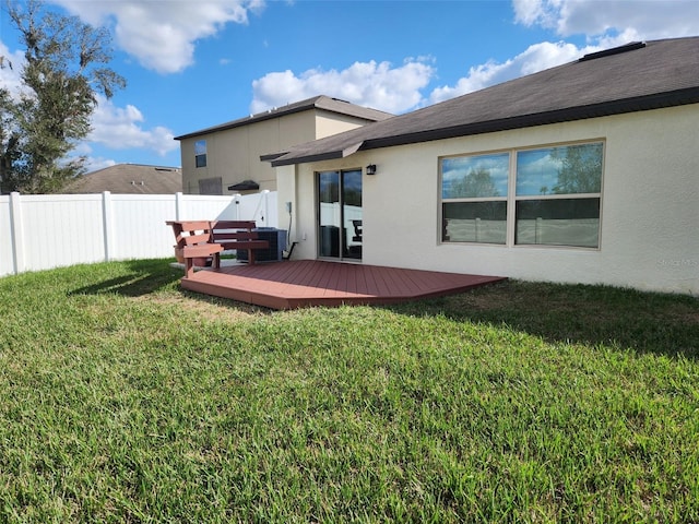 back of property featuring a deck and a lawn