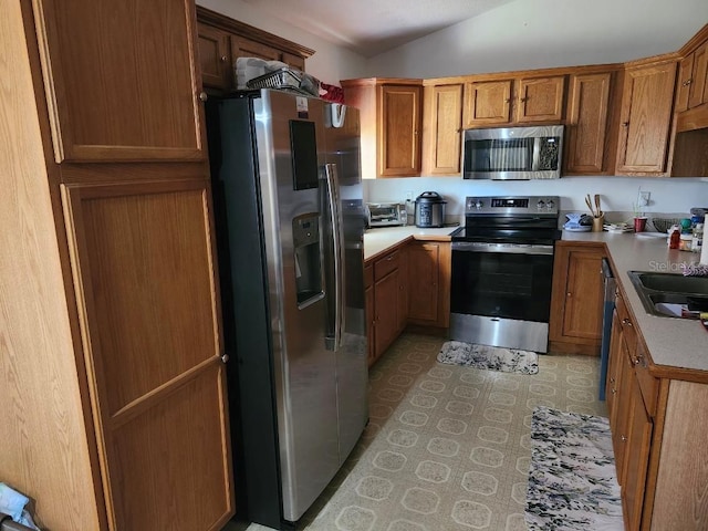 kitchen featuring light tile patterned floors, vaulted ceiling, stainless steel appliances, and sink