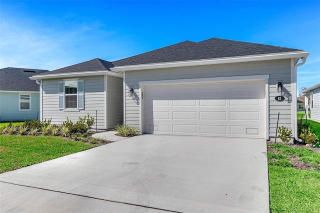 single story home featuring a shingled roof, a front yard, driveway, and an attached garage