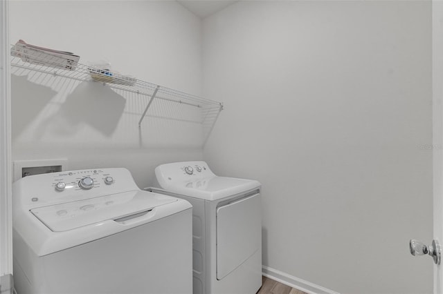 clothes washing area with hardwood / wood-style floors and washer and dryer