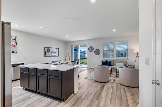 kitchen with a kitchen island with sink, stainless steel dishwasher, and light hardwood / wood-style flooring