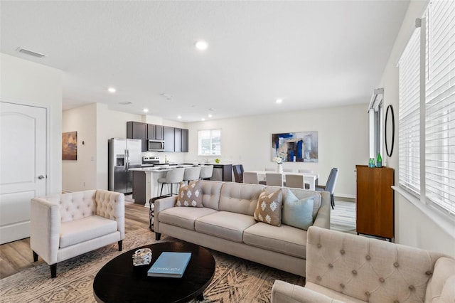 living room featuring light wood-style flooring, visible vents, and recessed lighting