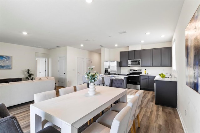 dining room with recessed lighting, light wood-style flooring, and baseboards