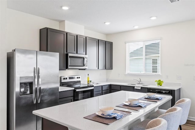 kitchen featuring a breakfast bar, a center island, stainless steel appliances, recessed lighting, and a sink