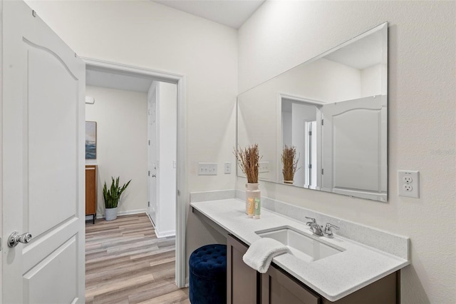 bathroom with wood finished floors, vanity, and baseboards