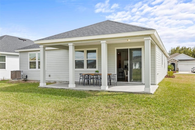 rear view of property with a yard, a shingled roof, and a patio area