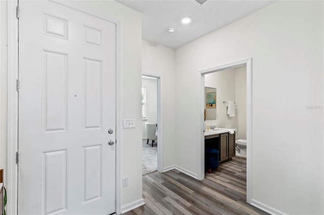 corridor featuring dark wood-style floors, a sink, and baseboards