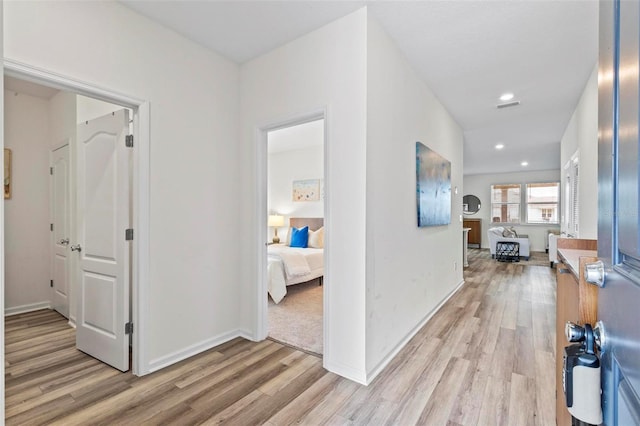 hall with visible vents, recessed lighting, light wood-style flooring, and baseboards