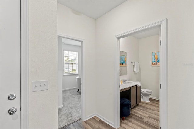 bathroom featuring baseboards, vanity, toilet, and wood finished floors