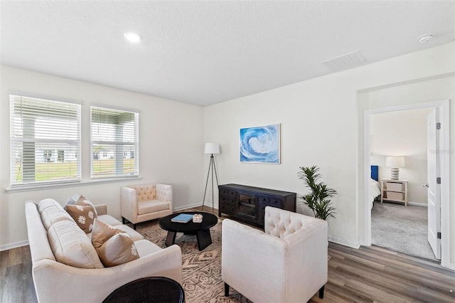 living room with baseboards, visible vents, and wood finished floors