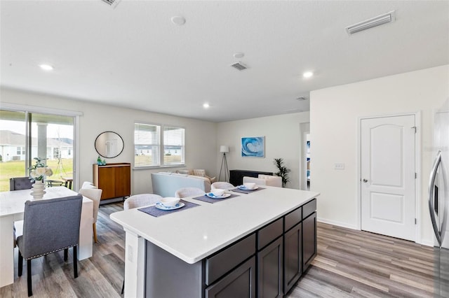 kitchen with a kitchen island, visible vents, light countertops, and open floor plan