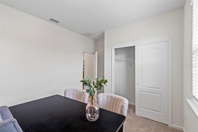 dining room with light colored carpet, visible vents, and baseboards