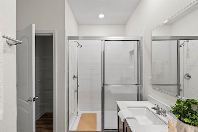 bathroom featuring a stall shower, a walk in closet, and vanity