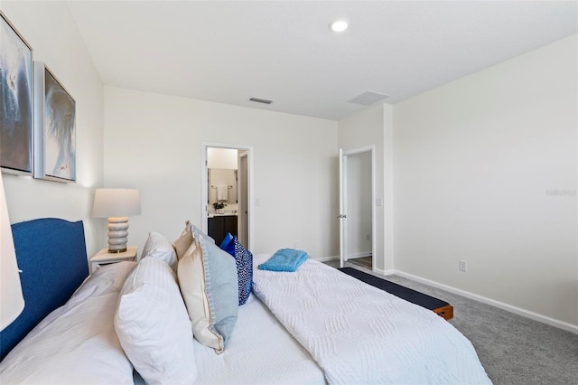 carpeted bedroom featuring ensuite bath, visible vents, and baseboards