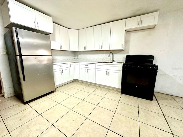 kitchen with white cabinets, sink, black range, and stainless steel refrigerator