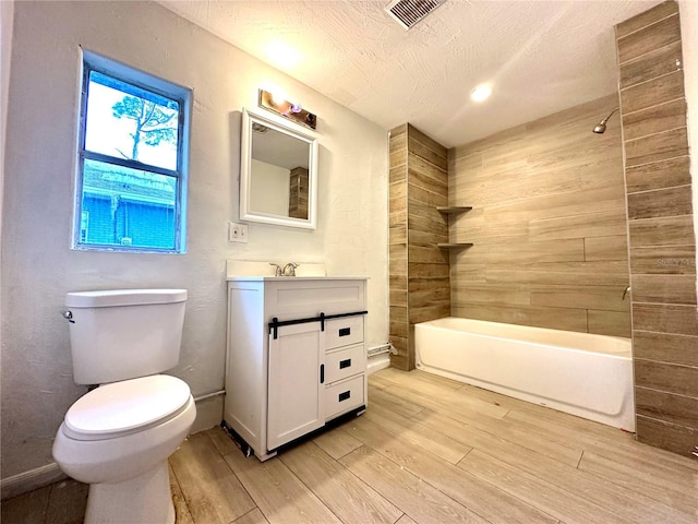 full bathroom featuring toilet, tiled shower / bath, a textured ceiling, vanity, and hardwood / wood-style floors