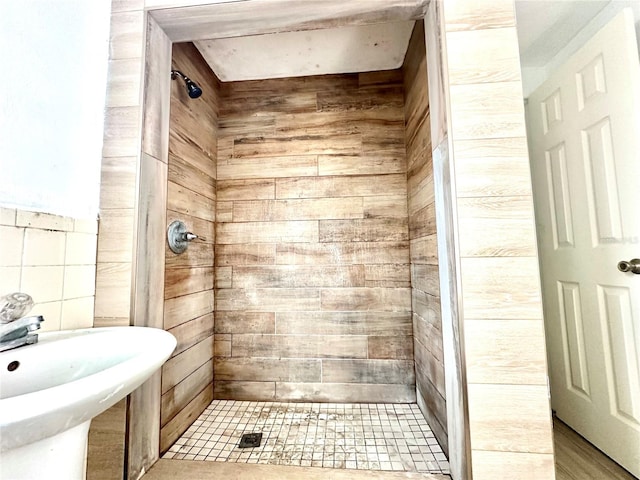 bathroom with a tile shower, sink, wooden walls, and tile walls