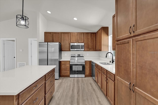 kitchen featuring pendant lighting, sink, lofted ceiling, light hardwood / wood-style flooring, and appliances with stainless steel finishes