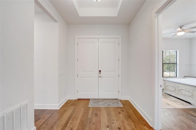 entrance foyer featuring ceiling fan, a raised ceiling, and light hardwood / wood-style flooring