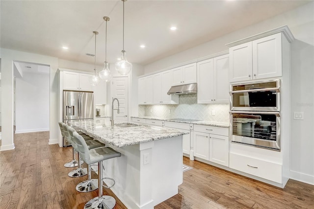 kitchen featuring pendant lighting, sink, appliances with stainless steel finishes, an island with sink, and white cabinets