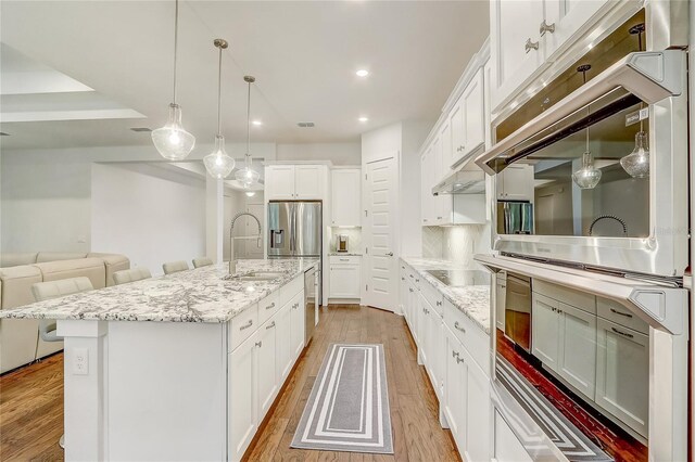 kitchen featuring sink, white cabinets, a kitchen breakfast bar, a large island, and light wood-type flooring