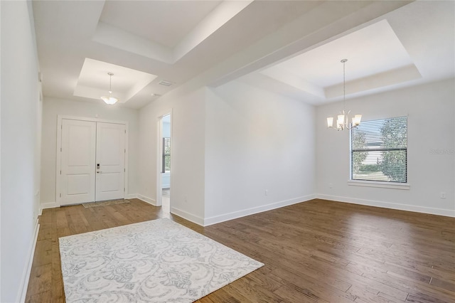 spare room featuring hardwood / wood-style flooring, a notable chandelier, and a tray ceiling