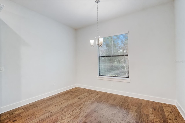 unfurnished dining area featuring hardwood / wood-style flooring and an inviting chandelier