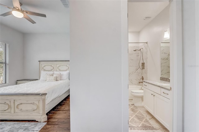 bedroom featuring ensuite bathroom, dark hardwood / wood-style floors, and ceiling fan