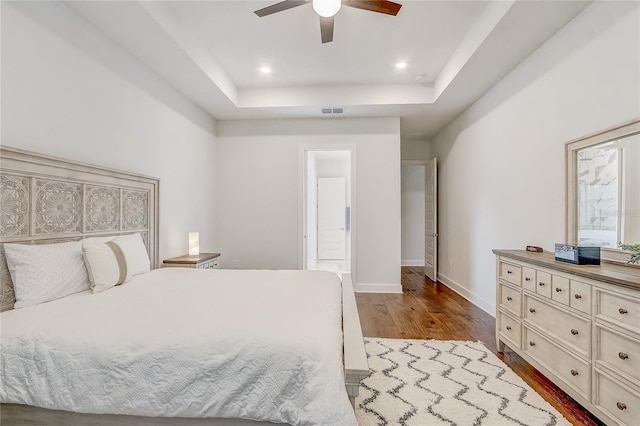 bedroom featuring ceiling fan, a raised ceiling, and light hardwood / wood-style floors