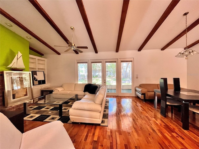 living room with vaulted ceiling with beams, ceiling fan with notable chandelier, hardwood / wood-style floors, and french doors