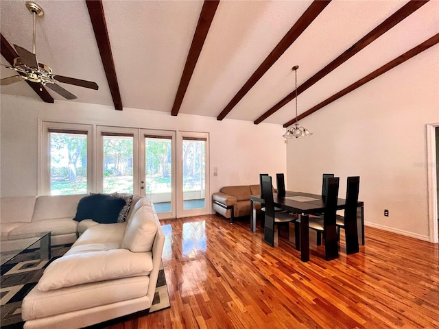 living room with wood-type flooring, vaulted ceiling with beams, ceiling fan with notable chandelier, and french doors