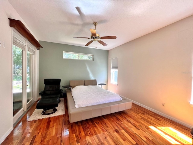 bedroom featuring multiple windows, wood-type flooring, ceiling fan, and a textured ceiling