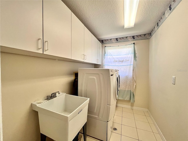 laundry room featuring light tile patterned flooring, sink, cabinets, washing machine and clothes dryer, and a textured ceiling