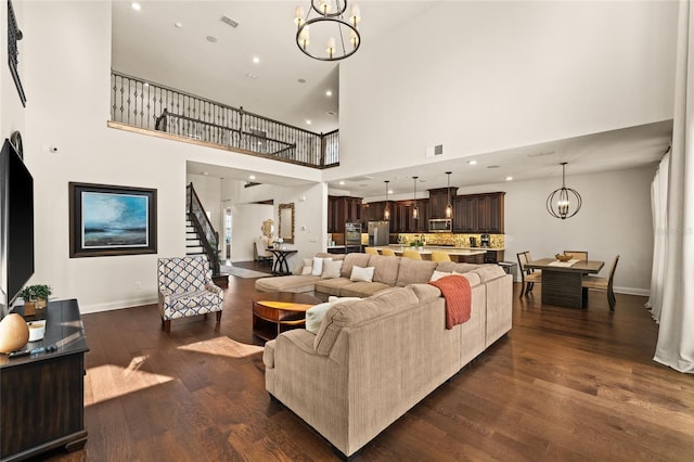 living room with dark hardwood / wood-style flooring, a notable chandelier, and a towering ceiling