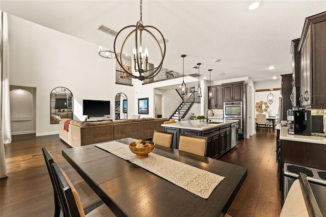 dining area featuring sink, a textured ceiling, dark hardwood / wood-style floors, and a chandelier